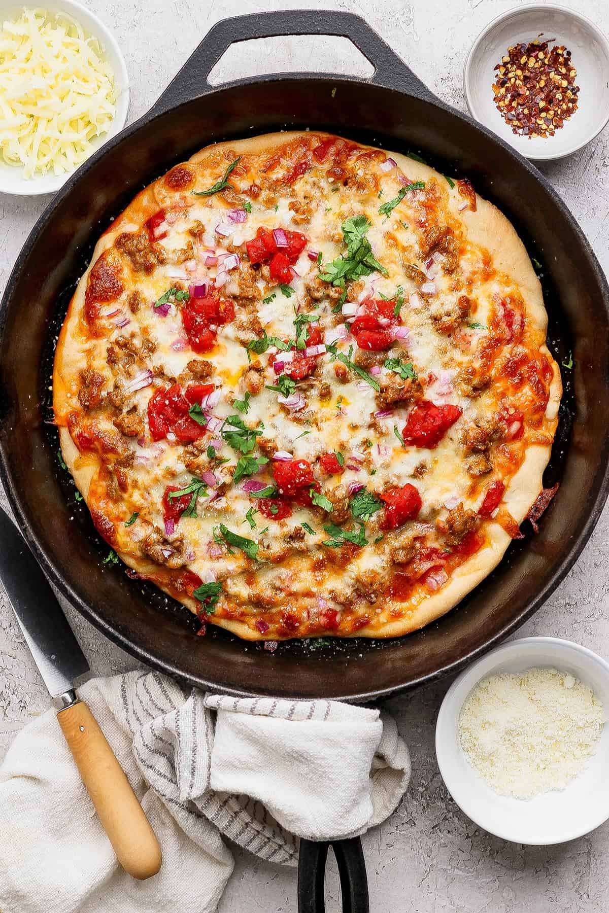 Cast iron skillet with sausage pizza.