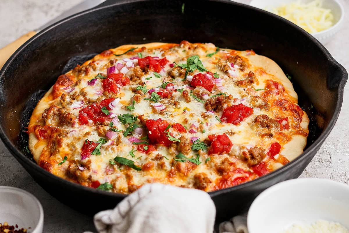 This skillet pizza with sausage has an Asian-inspired twist with chili garlic tomato sauce! A cast iron favorite with a crisp, chewy crust. Sausage pizza in cast iron skillet.
