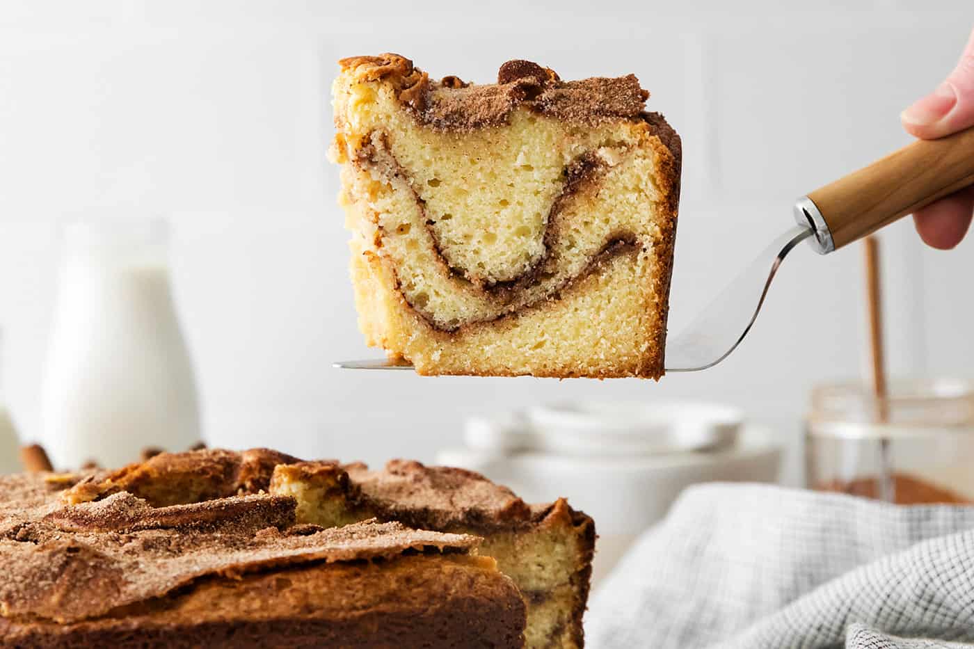 A spatula serving a slice of sour cream coffee cake with cinnamon ripple