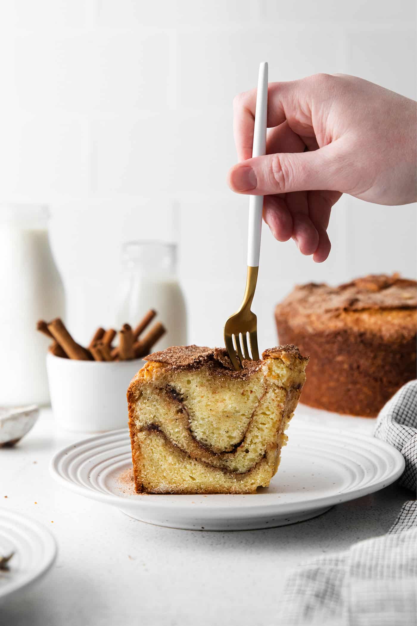 A fork digging into a slice of sour cream coffee cake