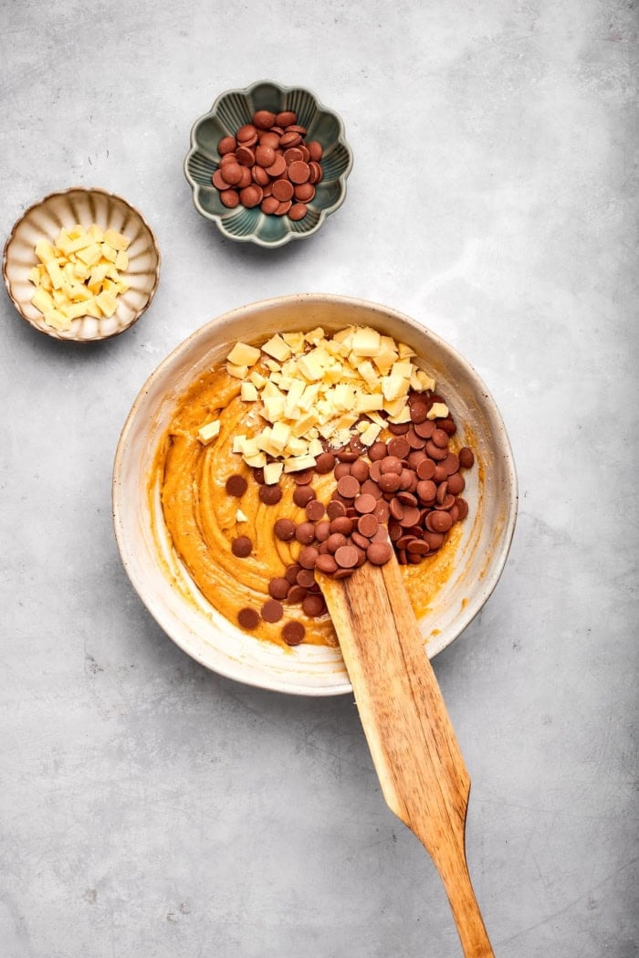 Stirring white and dark chocolate chips into dough for skillet cookie.
