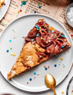 Brown butter chocolate chip skillet cookie slice on plate with sprinkles.