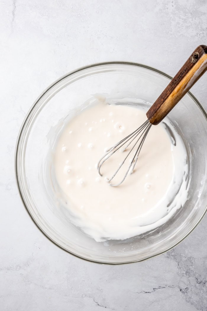 Bowl of vanilla glaze with whisk