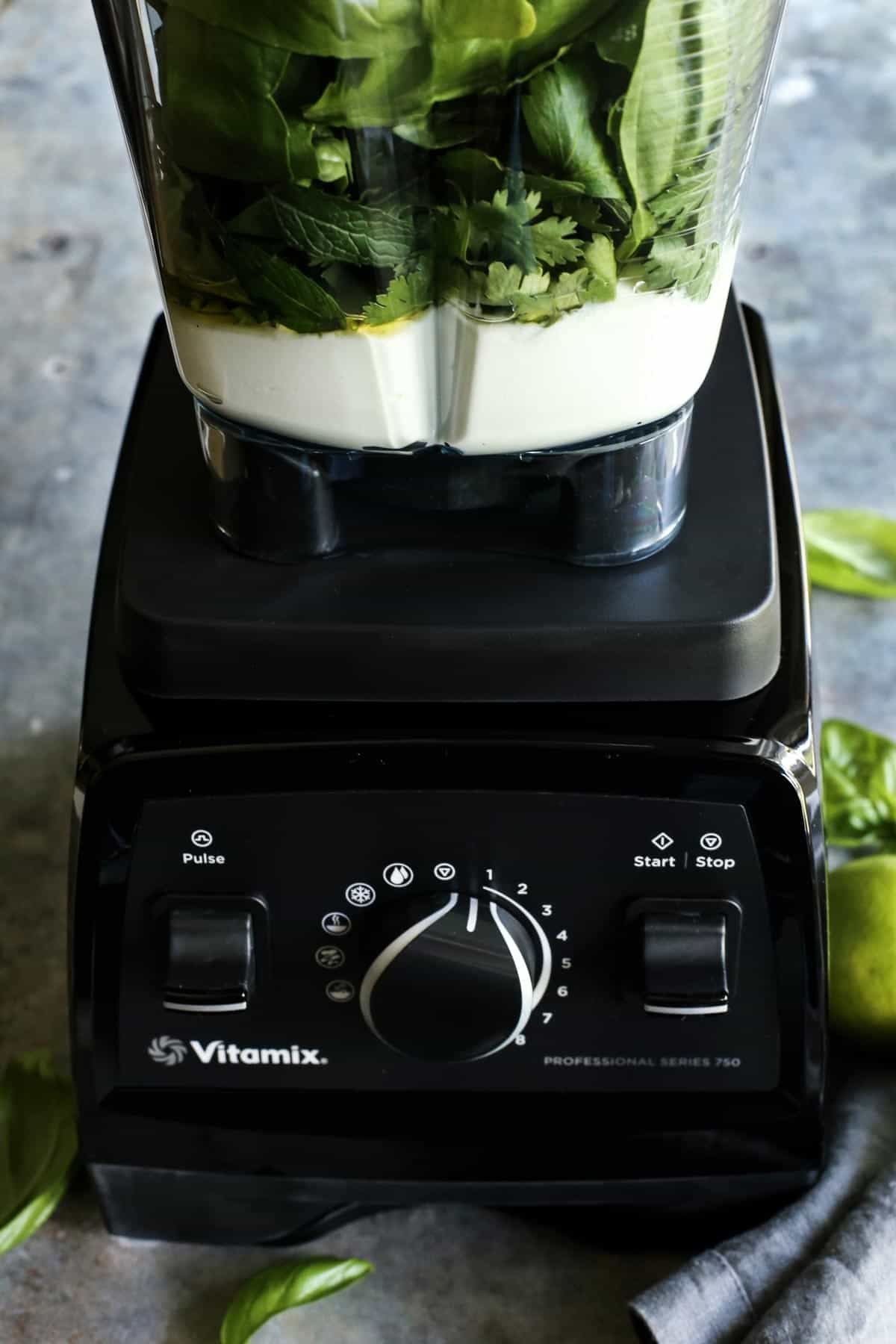 Vitamix blender carafe with green curry yogurt sauce ingredients, ready to be blended together