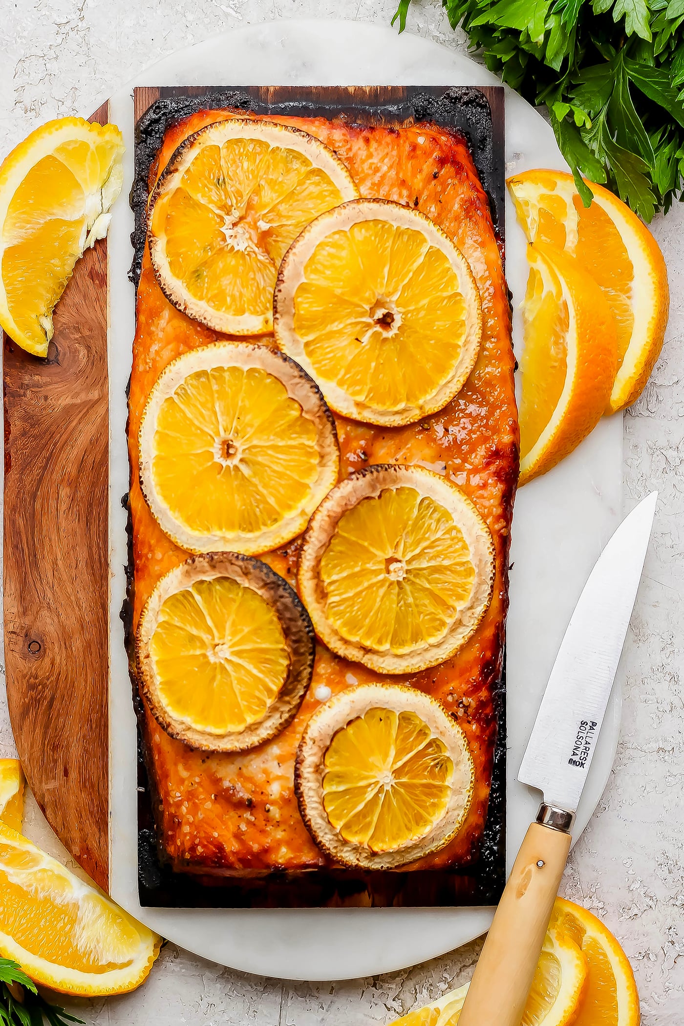 Grilled Chipotle-Orange Salmon is sweet, smoky and just a bit spicy, with irresistible caramelized edges. An easy recipe that feels special! Overhead view of grilled salmon fillet on cedar plank, topped with orange slices