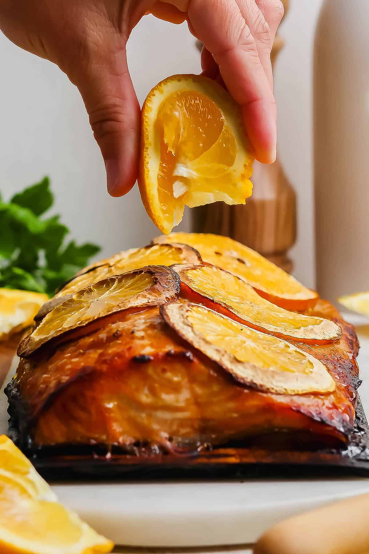 Grilled Chipotle-Orange Salmon is sweet, smoky and just a bit spicy, with irresistible caramelized edges. An easy recipe that feels special! Squeezing orange wedge over grilled chipotle-orange salmon