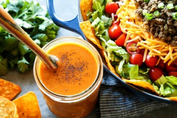 creamy taco salad dressing in a jar, beside fresh taco salad