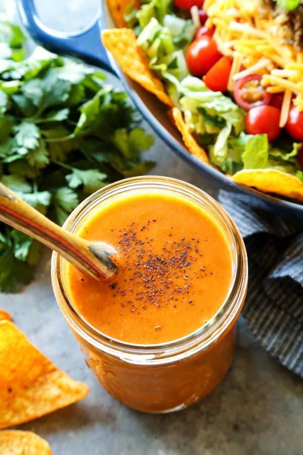 creamy taco salad dressing in a jar, beside fresh taco salad