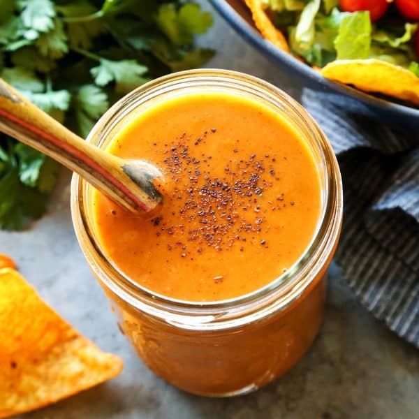 creamy taco salad dressing in a jar, beside fresh taco salad