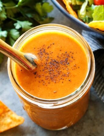 creamy taco salad dressing in a jar, beside fresh taco salad