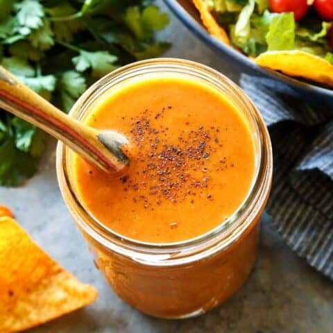 creamy taco salad dressing in a jar, beside fresh taco salad