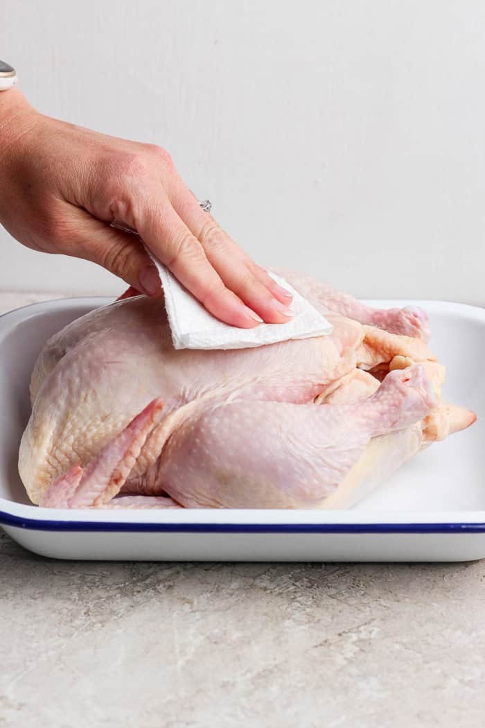Using paper towels to dry whole chicken in pan