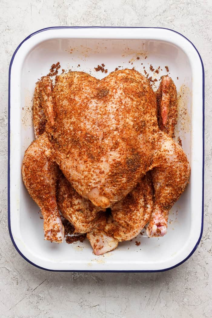 Overhead view of seasoned whole chicken in pan