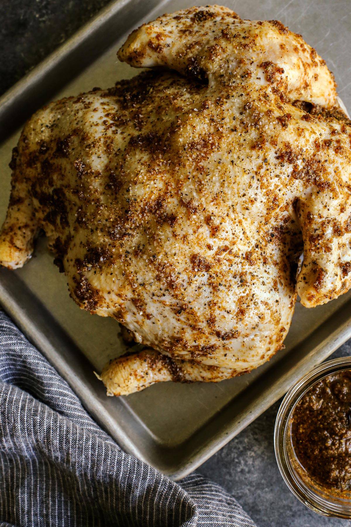 a raw, whole chicken rubbed with seasoning