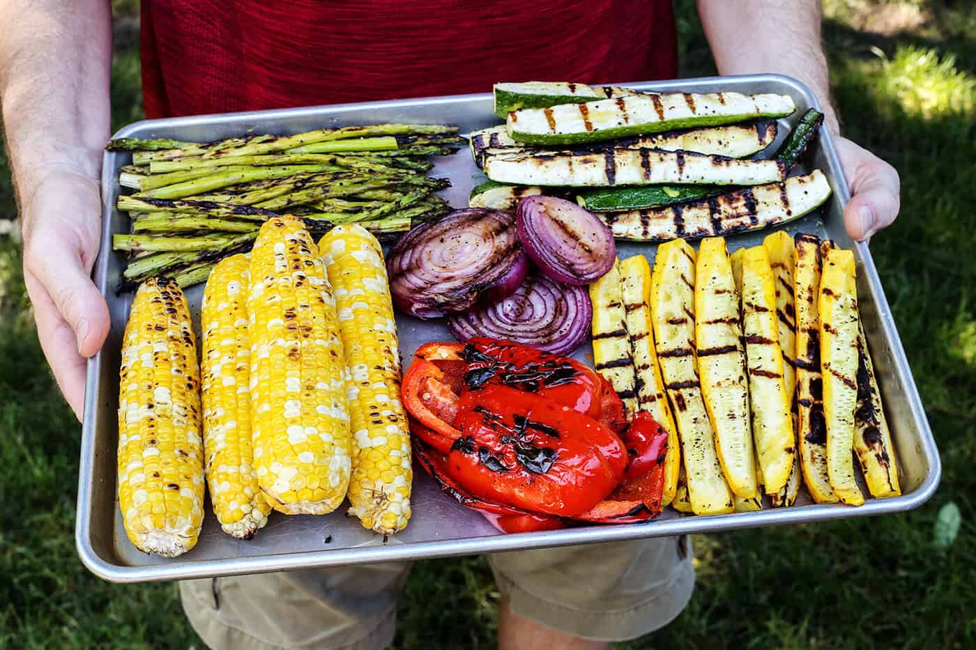 Hands holding pan of grilled vegetables