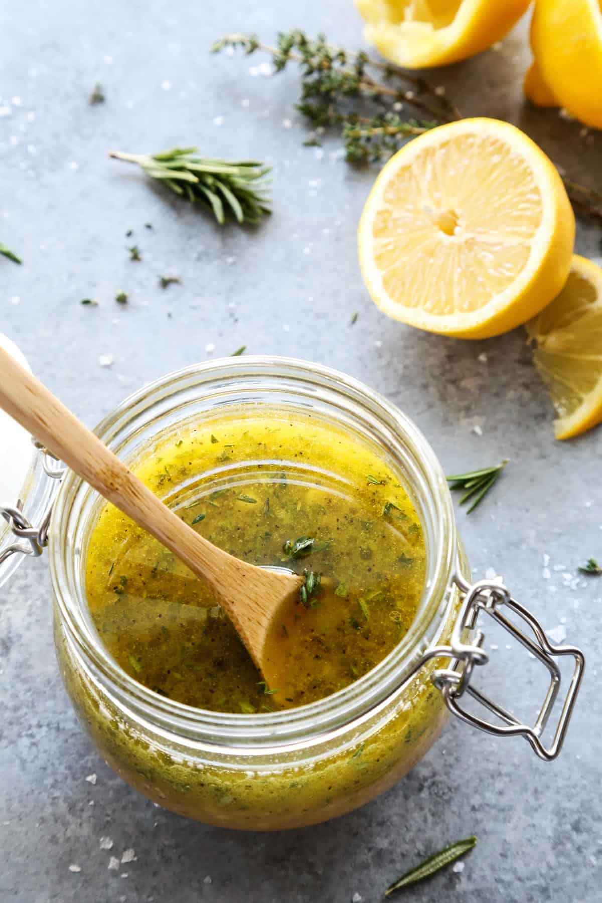 jar of herby lemon vinaigrette with a wooden spoon