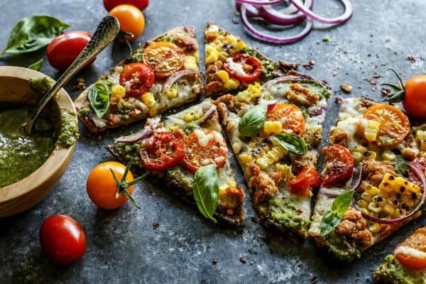 grilled flatbread pizza topped with pesto and fresh tomatoes and corn