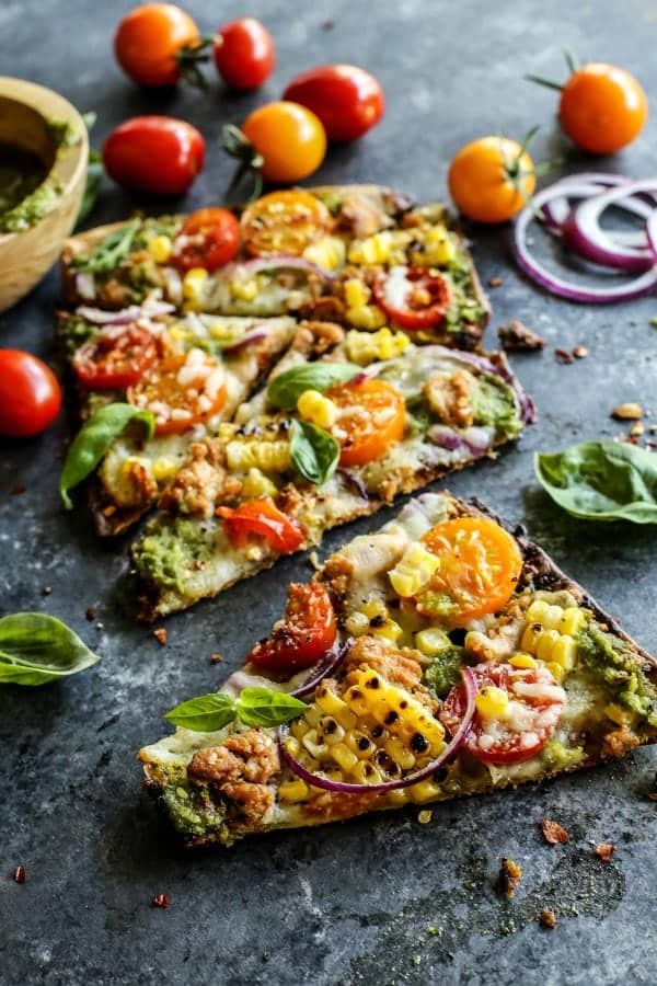 grilled pizza topped with fresh corn, tomatoes, onion, and basil