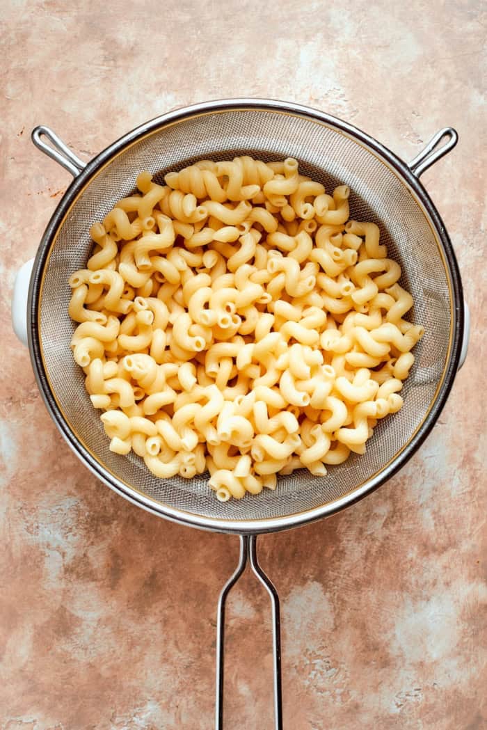 This sun-dried tomato pasta salad lets the abundance of summer produce shine, with juicy tomatoes and fresh basil. Perfect for picnics! Pasta in colander.