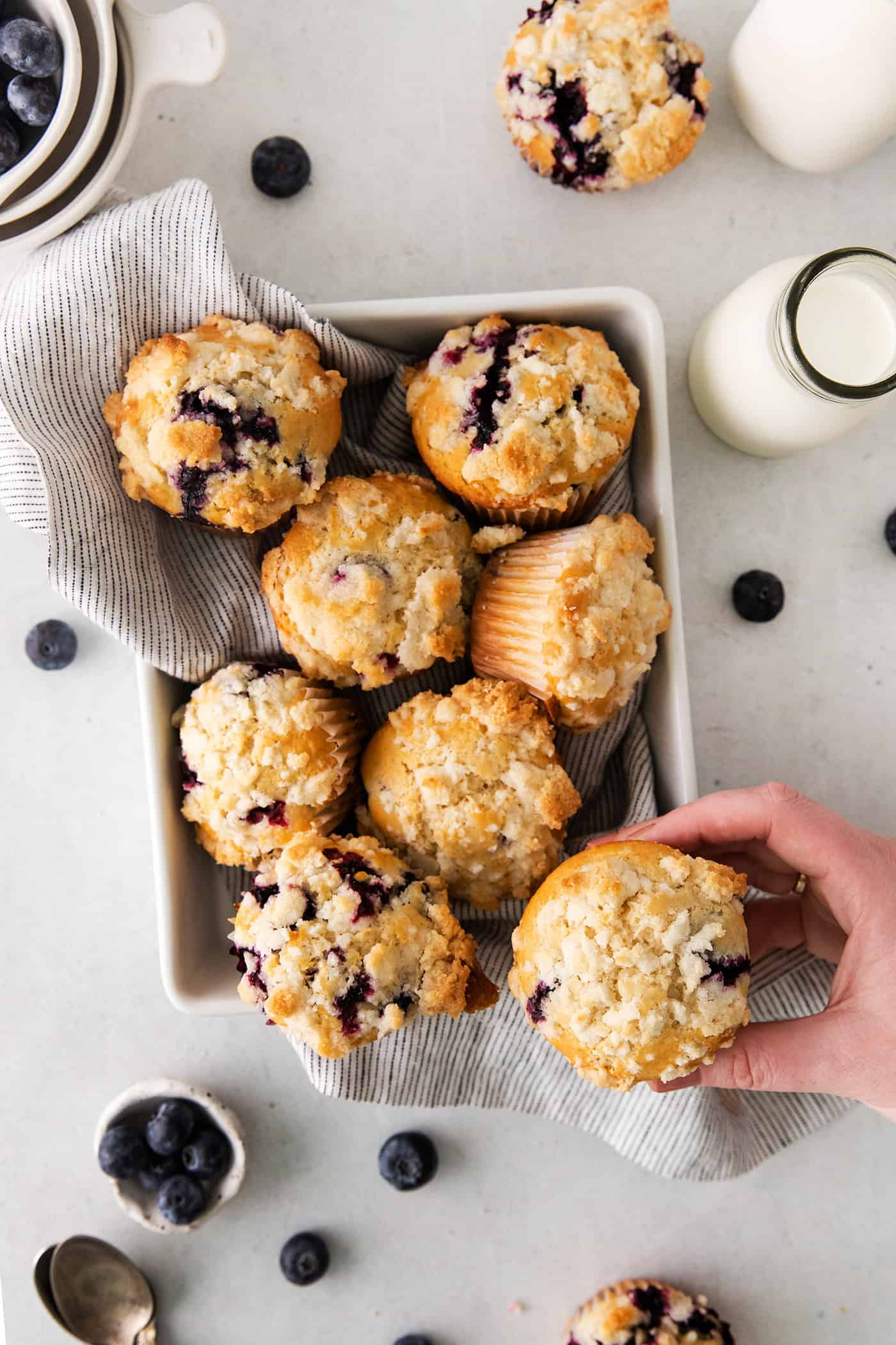 Overhead view blueberry muffins with a hand holding one