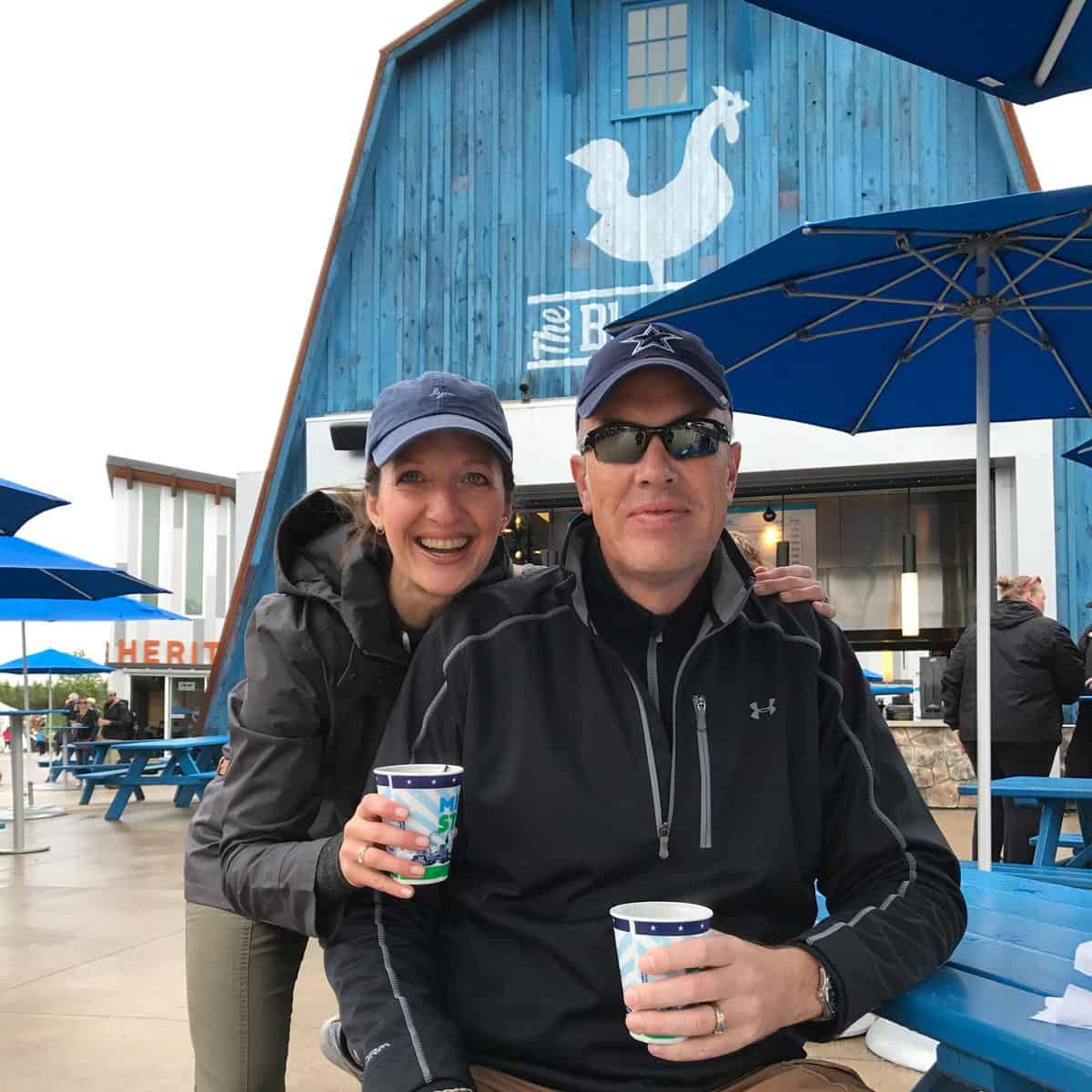 a couple holding cups of coffee in front of The Blue Barn