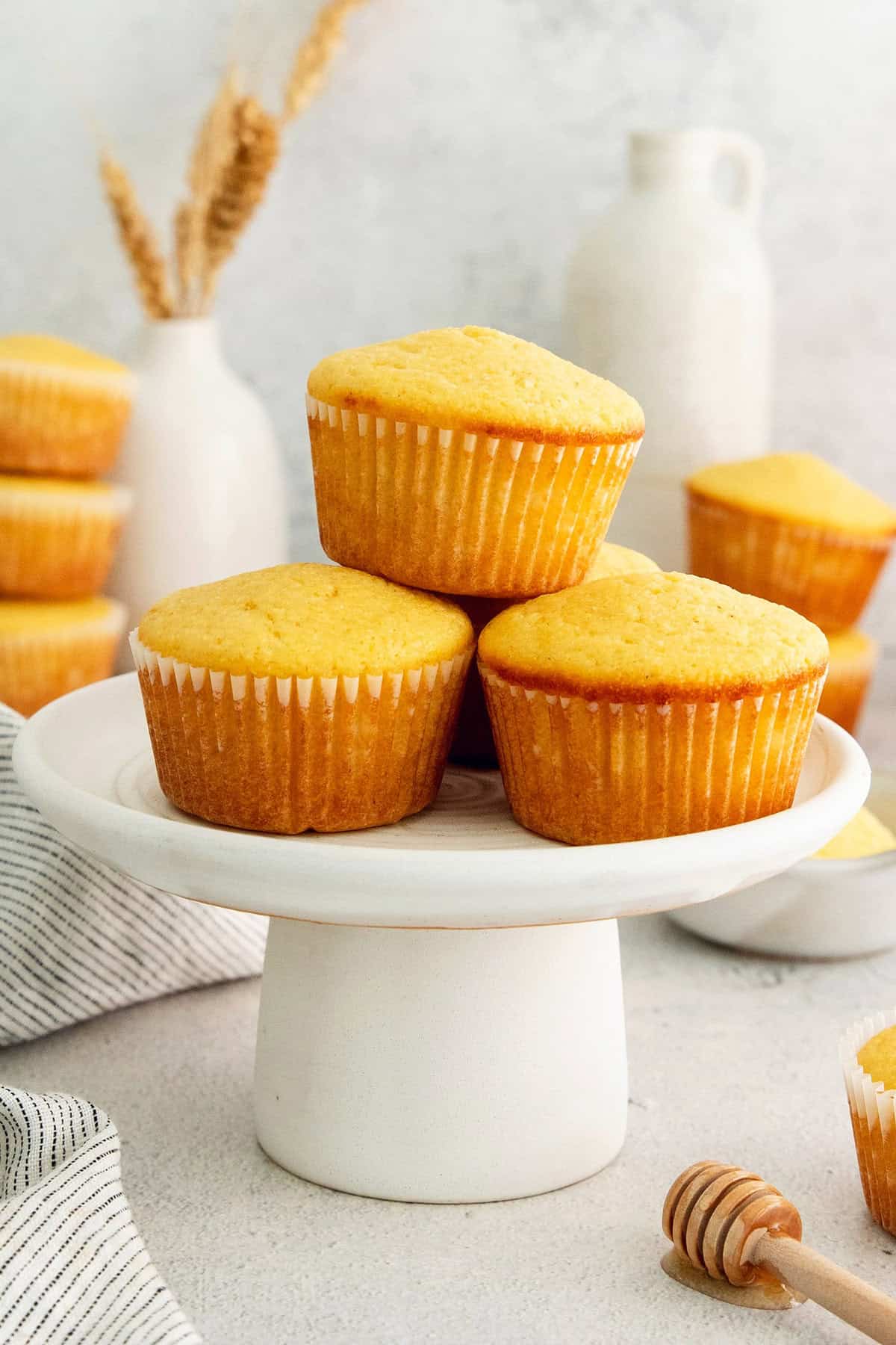 Three freshly-baked honey cornbread muffins on a cake stand.