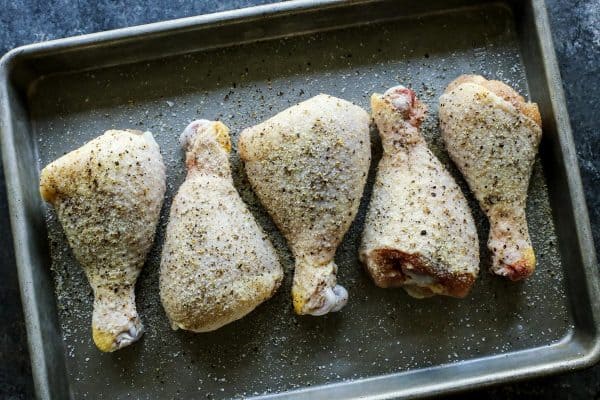 raw chicken drumsticks on a pan