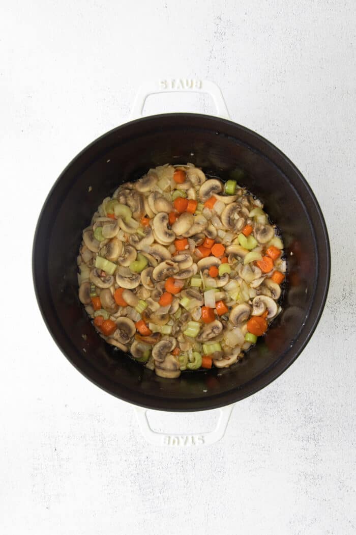 Overhead view of shredded chicken and vegetables in a stock pot.