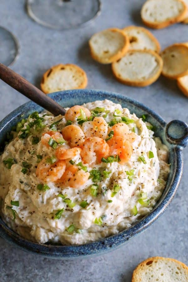 blue bowl filled with cold shrimp dip, plus baguette crackers for dipping