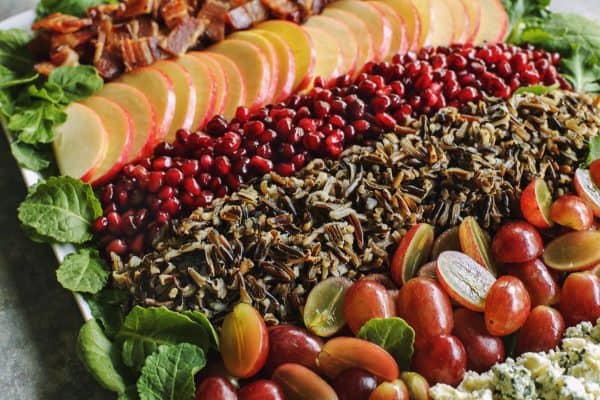 close-up photo of salad with wild rice, grapes, pomegranates, bacon, apples