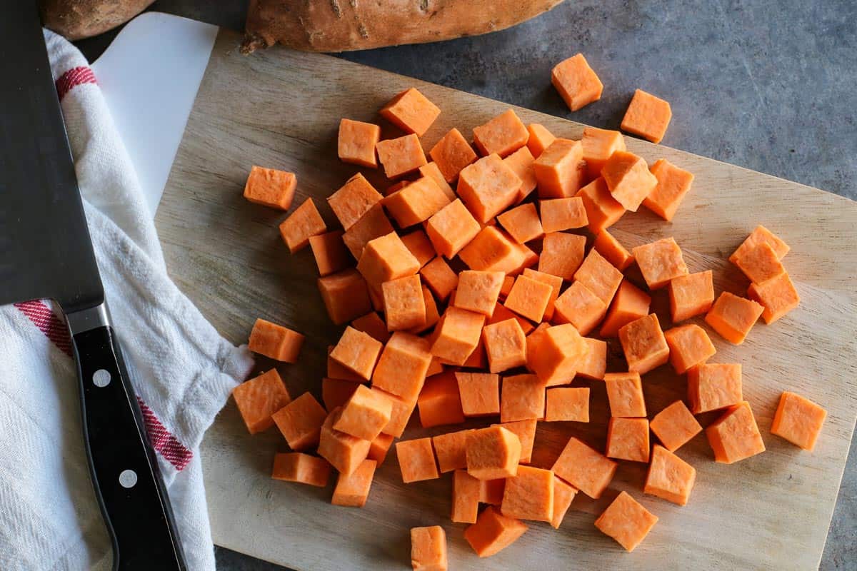 Overhead view of cubed sweet potatoes on cutting board.