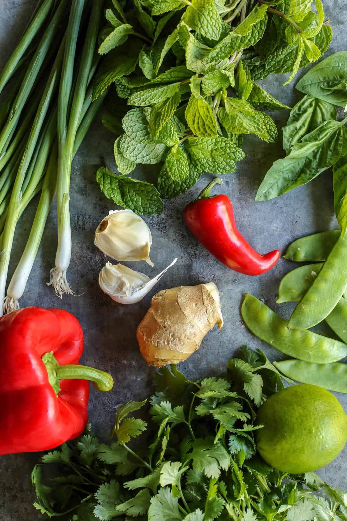 Overhead view of fresh vegetables and herbs on a countertop.