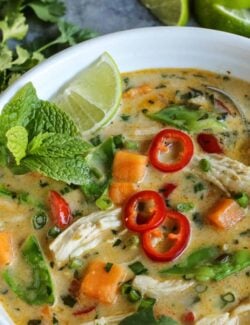 Thai Chicken Soup in a white bowl garnished with fresh mint and sliced chilies.