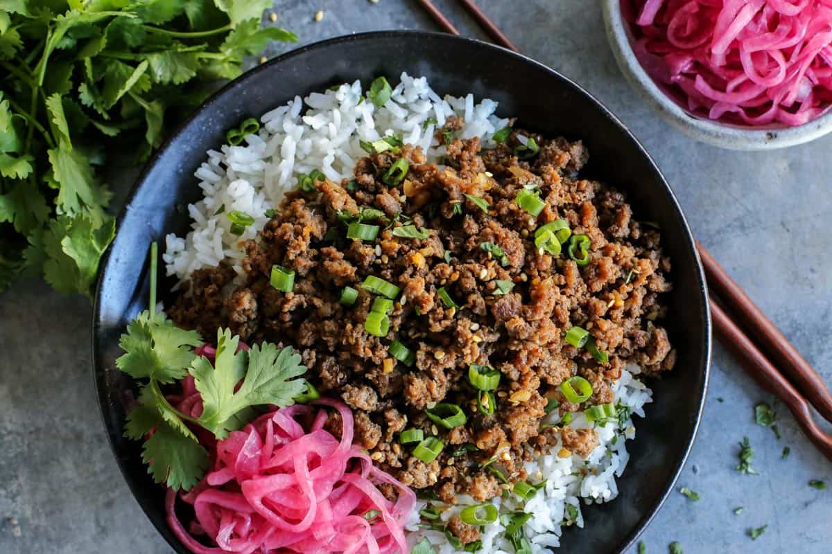 A black bowl with rice and Korean beef. 