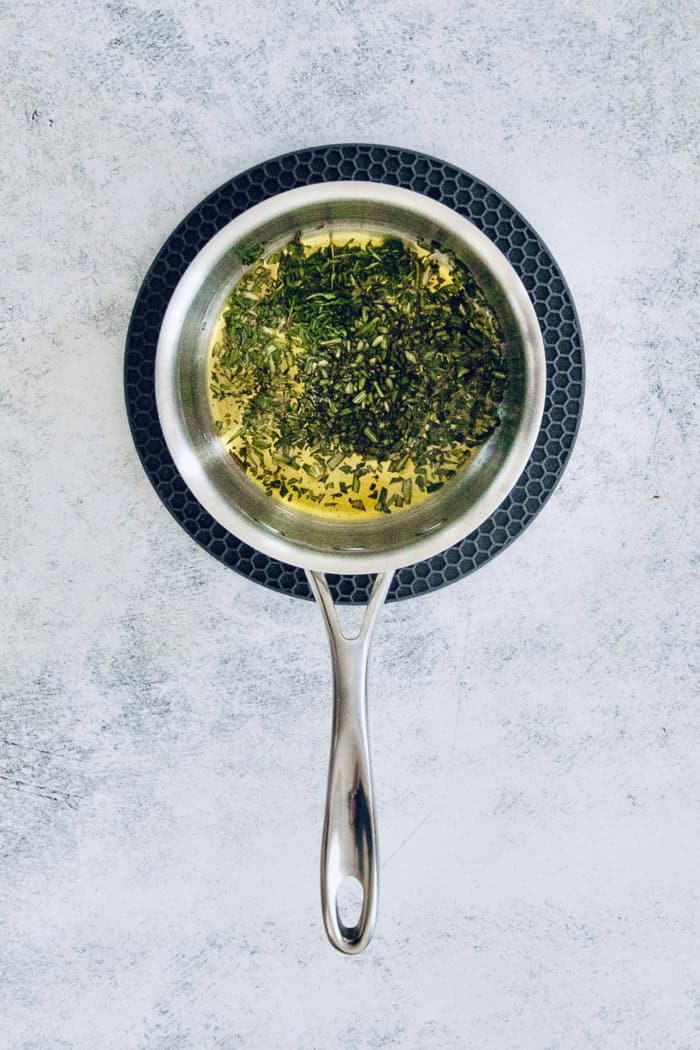 Infusing the olive oil with rosemary and thyme in a pot. 