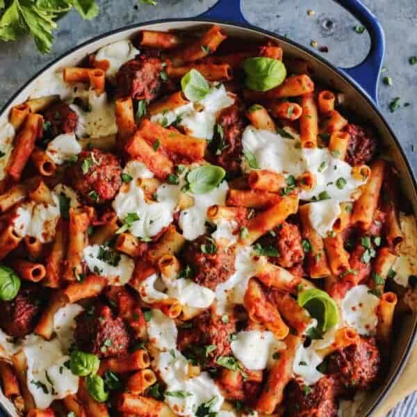 ziti pasta with meatballs in tomato sauce, in a blue casserole dish