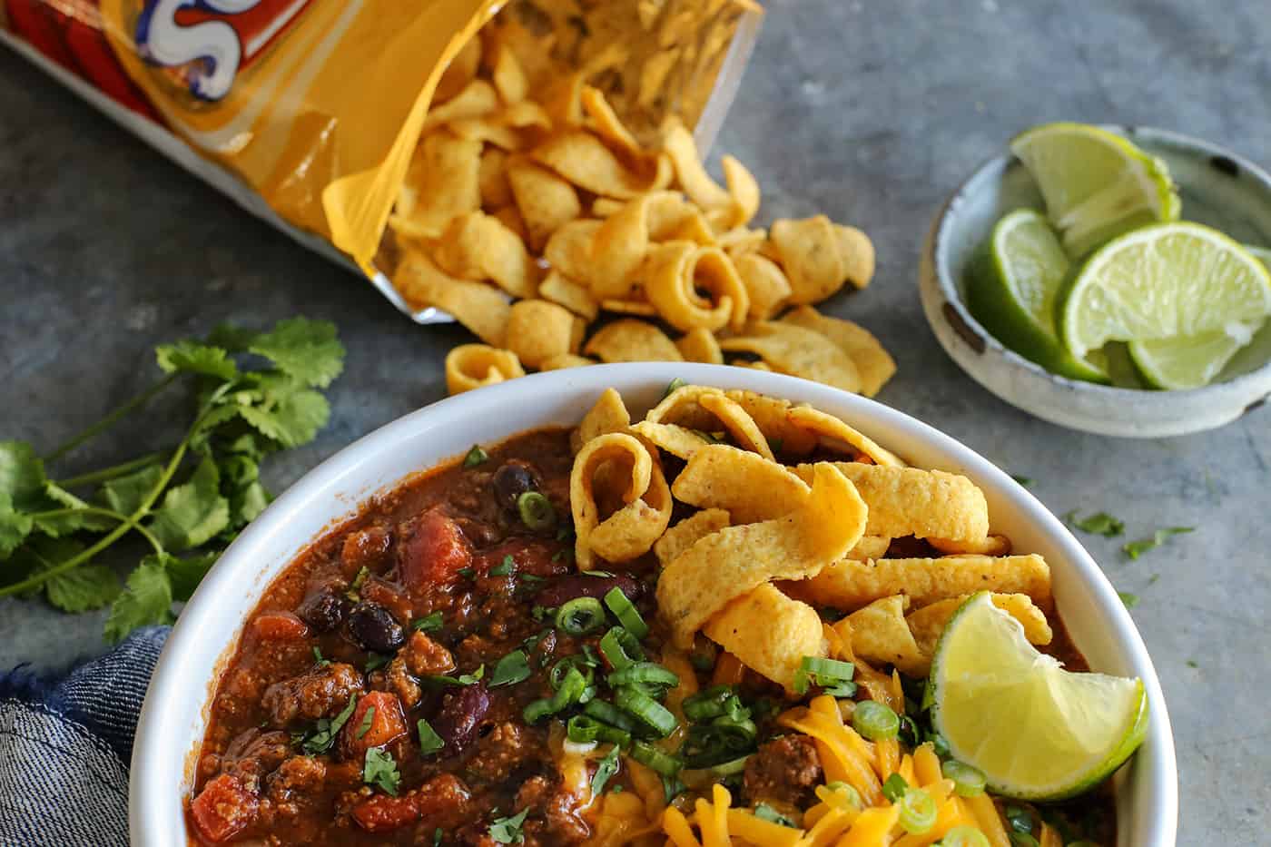 A bowl of beef chili topped with Fritos