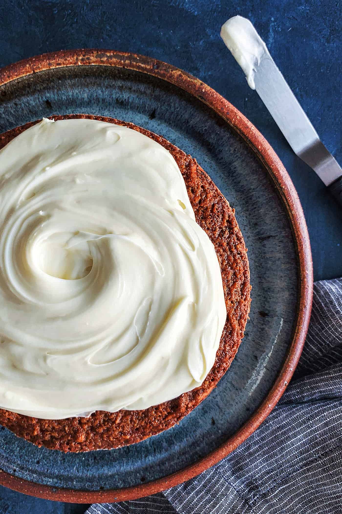 Cream cheese icing spread on top of carrot cake