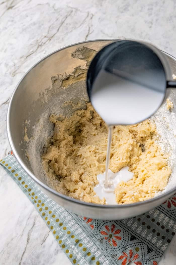 Pouring coconut milk into bowl of batter