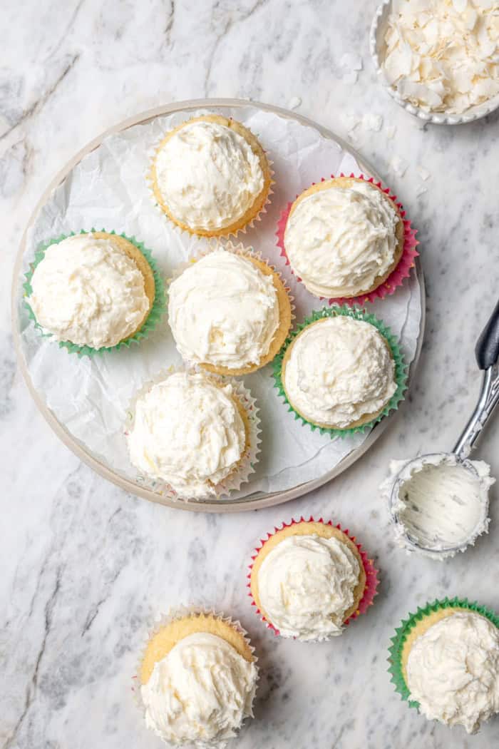 Overhead view of coconut cupcakes on plate and marble countertop