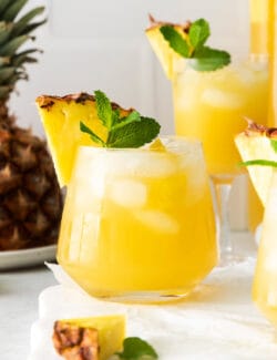 Three pineapple mint julep sangrias garnished with a pineapple slice