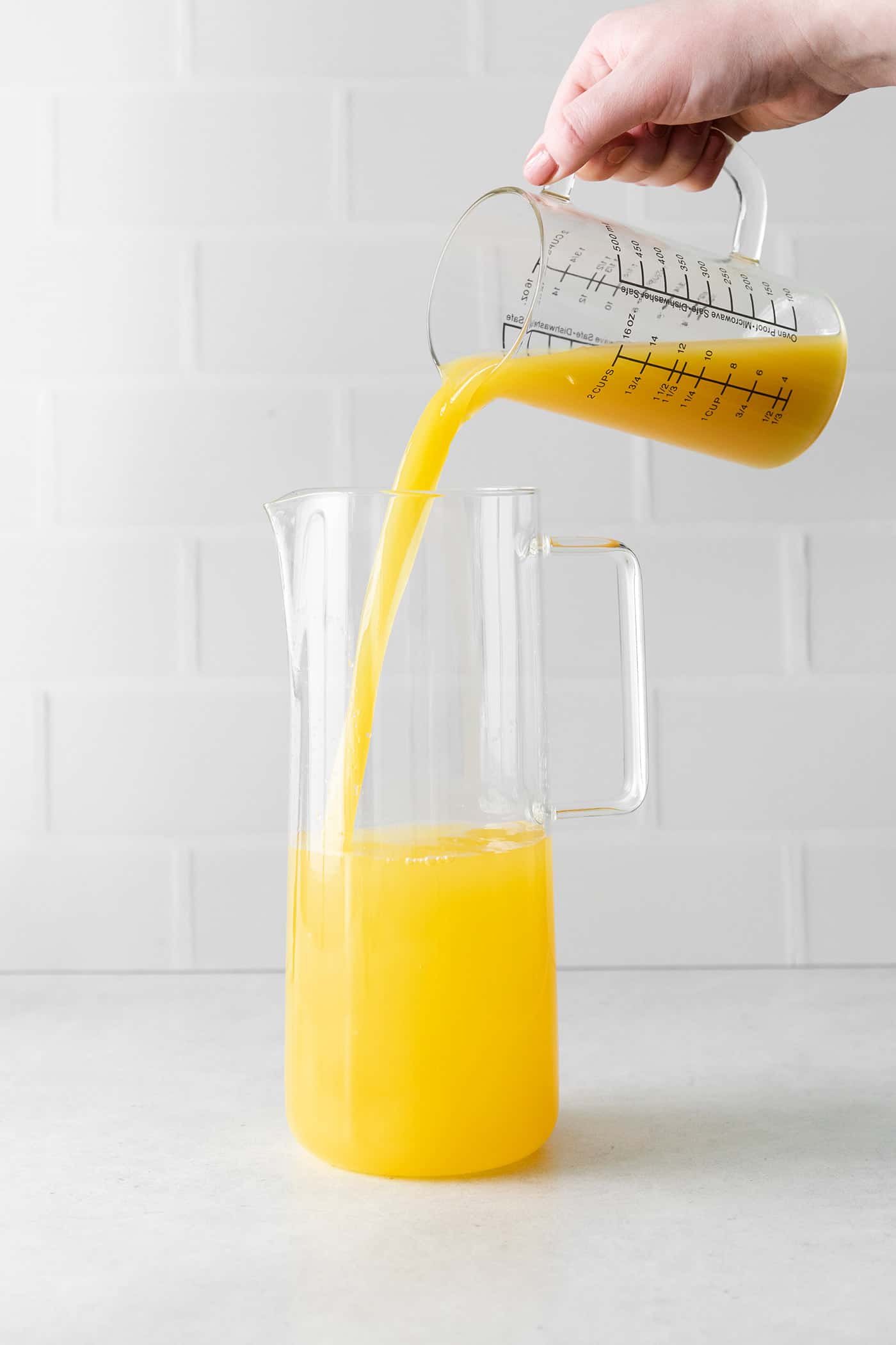 Orange juice being added to a pitcher with wine