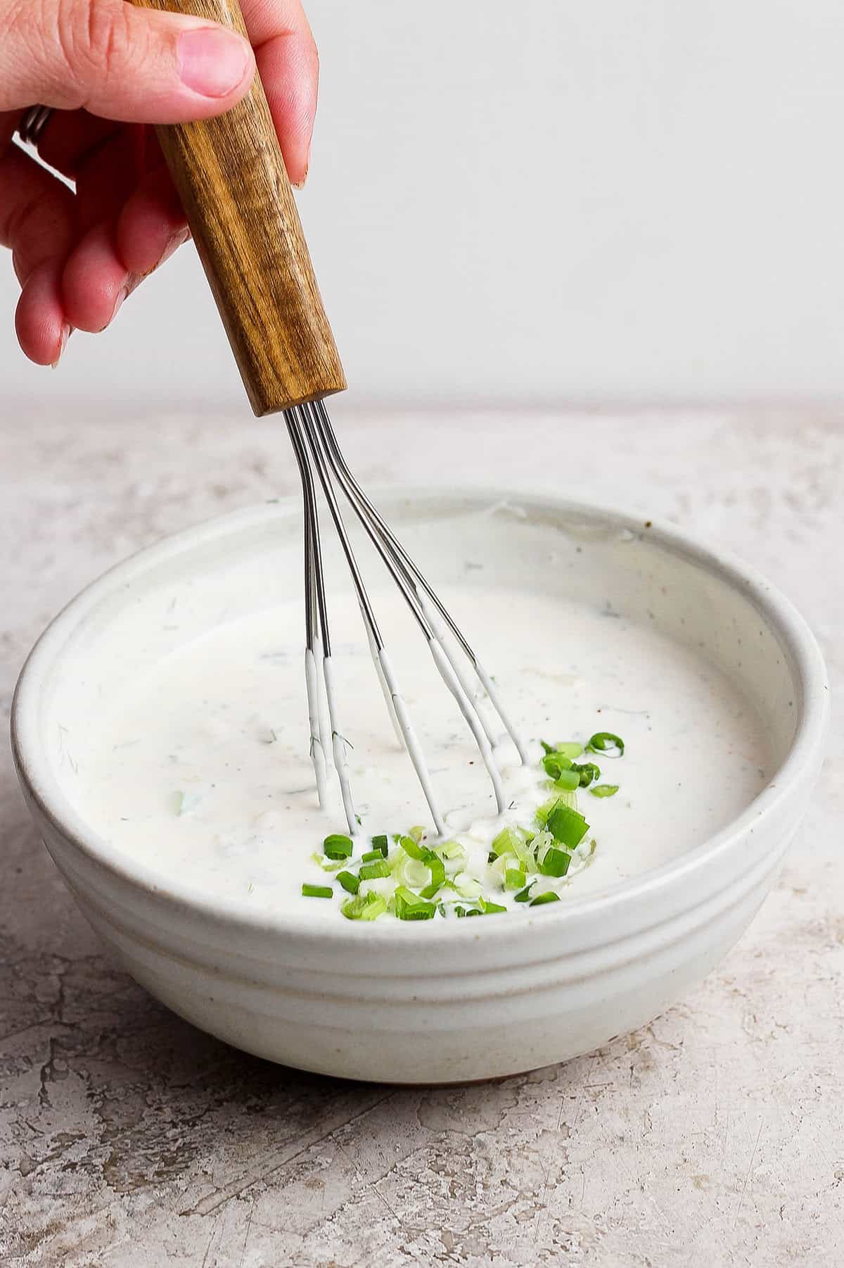 Whisking buttermilk ranch dressing in bowl