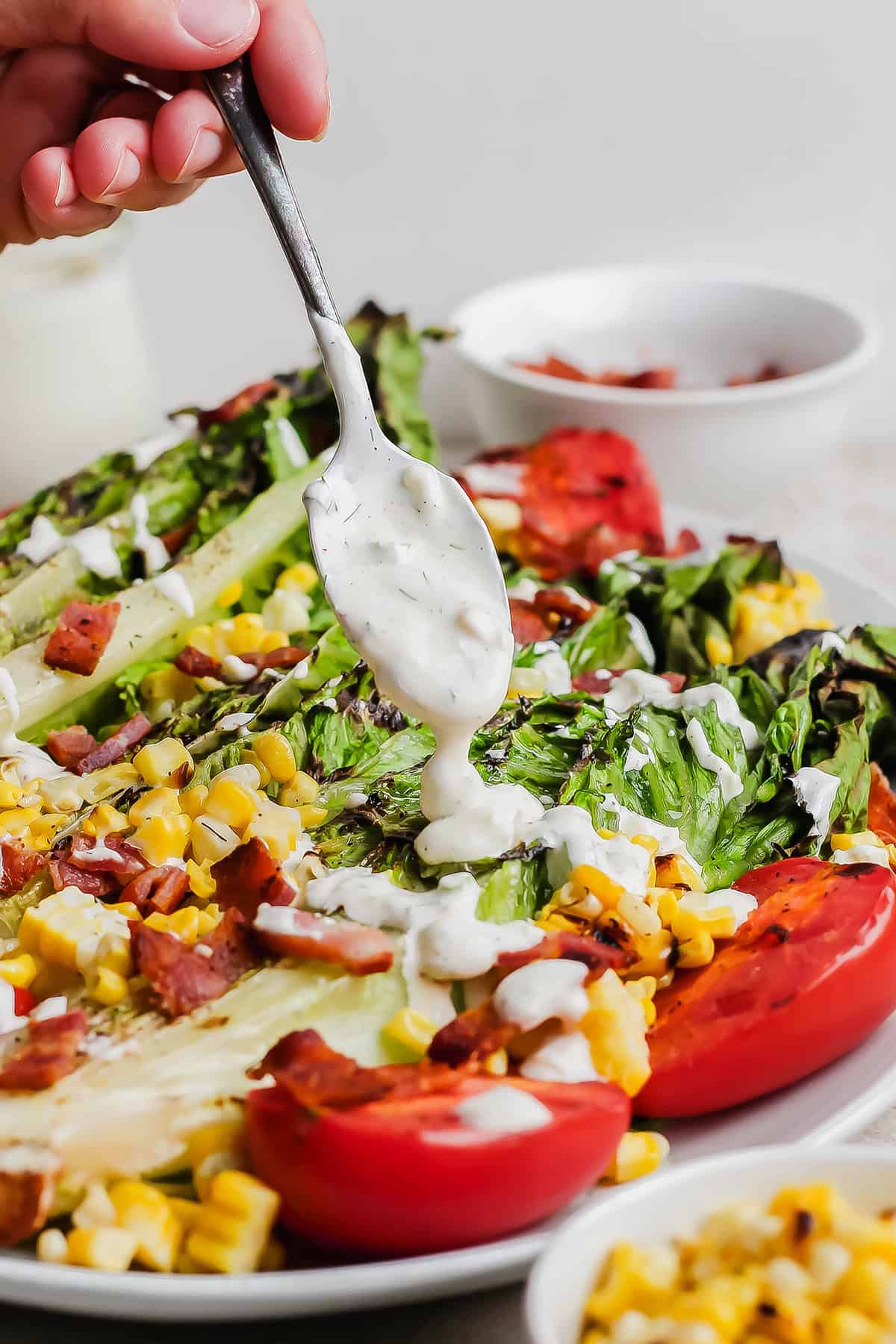 Spooning buttermilk ranch dressing over salad on plate