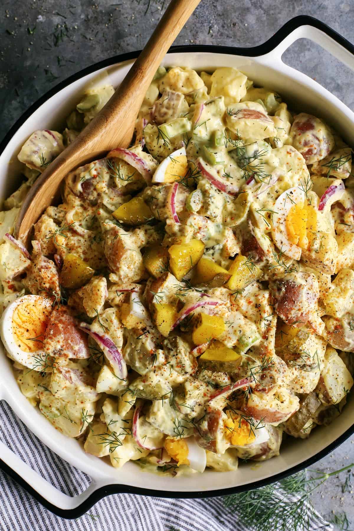 Dill pickle potato salad with hard boiled eggs in a bowl.