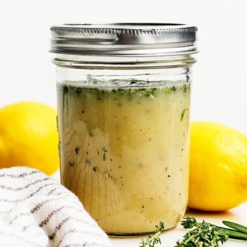 Homemade lemon vinaigrette with fresh herbs in jar