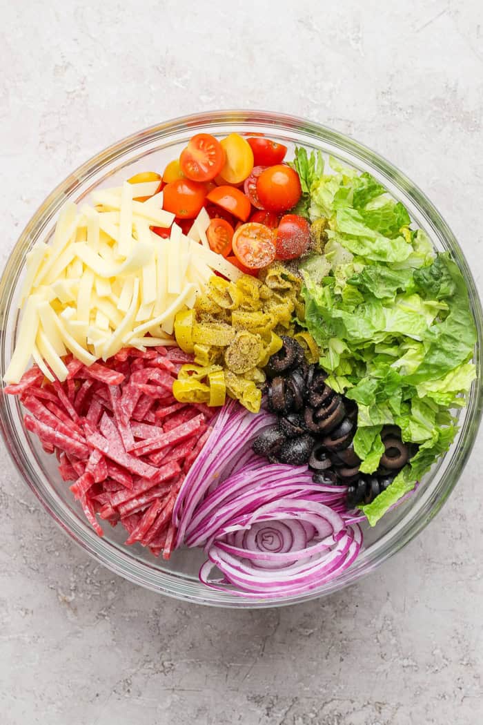 Overhead view of Italian chopped salad ingredients in bowl before tossing