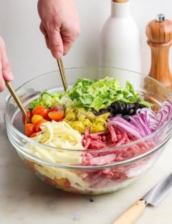 Tossing Italian chopped salad in large glass bowl