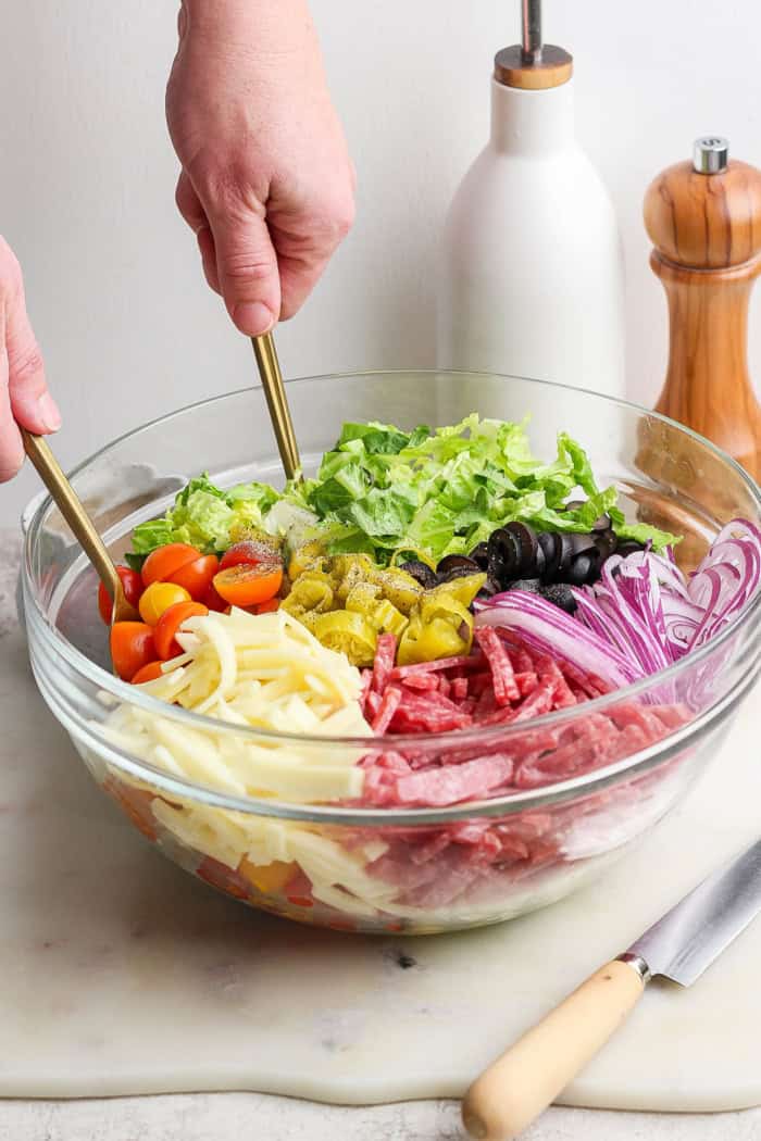 Tossing Italian chopped salad in large glass bowl
