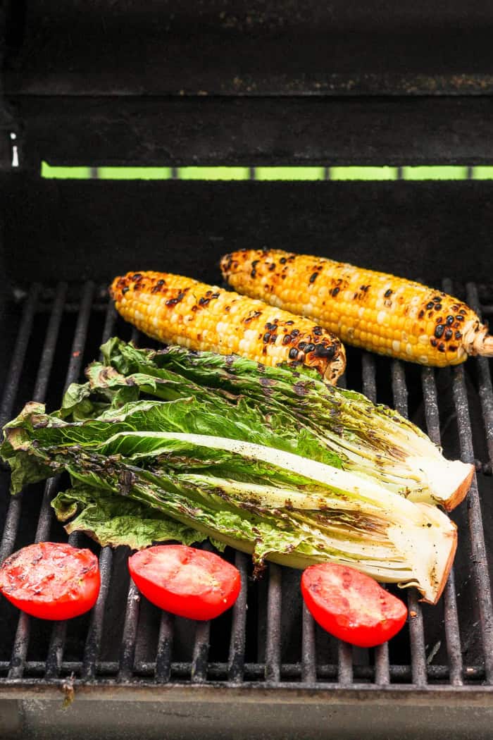 This smoky Grilled Romaine Salad is simple and summery, with tomatoes, sweet corn, crispy bacon and homemade buttermilk ranch dressing. Yum! Romaine, roma tomatoes, and 2 ears of corn on grill